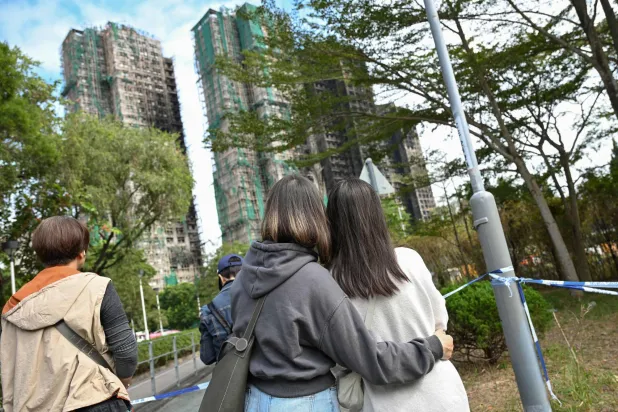 People look up at the Wang Fuk Court apartment blocks in the aftermath of the deadly November 26 fire in Hong Kong's Tai Po district on December 1, 2025. (AFP)
