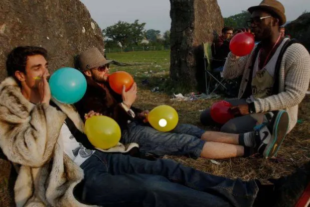 أشخاص يستنشقون غاز الضحك باستخدام البالونات (رويترز)