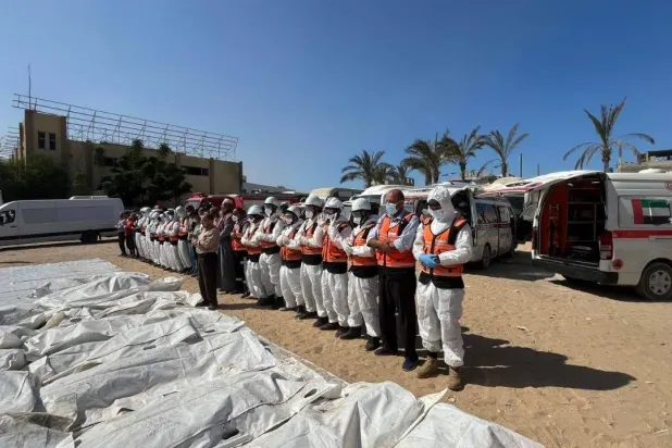 عناصر من الدفاع المدني الفلسطيني يؤدون صلاة الجنازة على عدد من الجثامين قبل دفنهم (الدفاع المدني الفلسطيني عبر «تلغرام»)