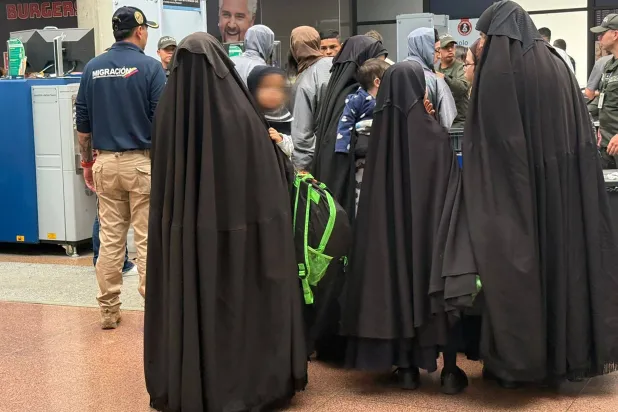 صور نشرتها السلطات تظهر أعضاء طائفة «ليف طاهور» وهم يرتدون سترات سوداء طويلة خلال مرورهم عبر نقاط تفتيش أمنية في المطار (أ.ف.ب)