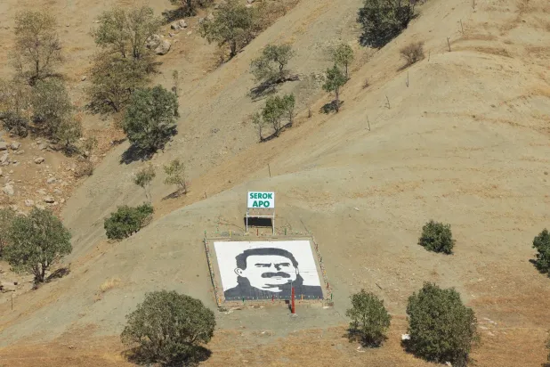 صورة لزعيم حزب العمال الكردستاني السجين عبد الله أوجلان ثبتها مسلحون من الحزب عند سفح جبل قنديل شمال العراق عند إعلان انسحابهم من تركيا في 26 أكتوبر الماضي (رويترز)