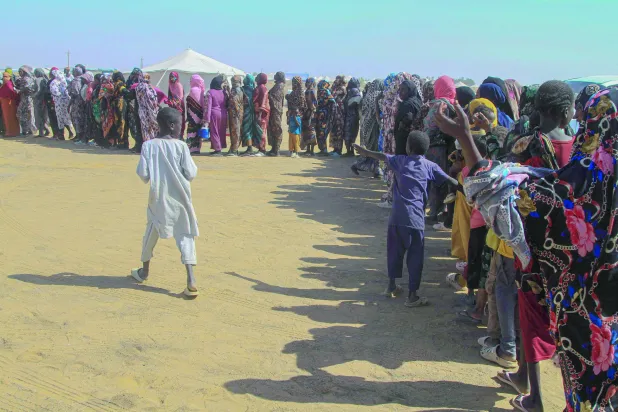 سودانيات نزحن من الفاشر يتلقين مساعدات داخل مخيم في بلدة العفاض شمال السودان (أ.ف.ب)