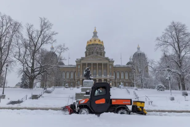 Workers remove snow from the sidewalk outside of the Iowa State Capitol Building after a snowstorm left several inches of snow in Des Moines, Iowa, US, January 9, 2024. REUTERS/Alyssa Pointer/File Photo