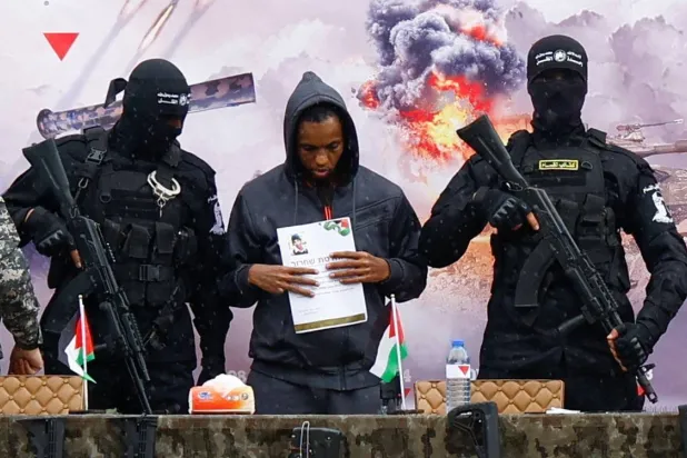 Israeli captive Avera Mengistu stands on the handover platform as part of a prisoner exchange agreement between Hamas and Israel in Rafah in February (Reuters)