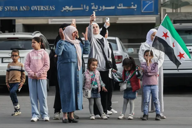  سوريون يتابعون من جانب الطريق سيارات وزارة الداخلية خلال الإطلاق الرسمي لهويتها البصرية الجديدة في دمشق (أ.ب)