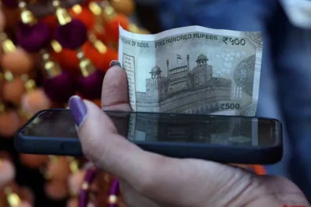 امرأة تمسك بورقة نقدية فئة 500 روبية في الأحياء القديمة لدلهي (رويترز)