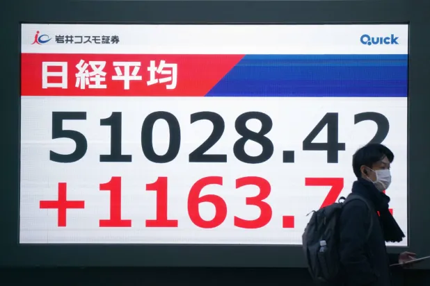 رجل يمر أمام شاشة تعرض حركة الأسهم في وسط العاصمة اليابانية طوكيو (أ.ف.ب)