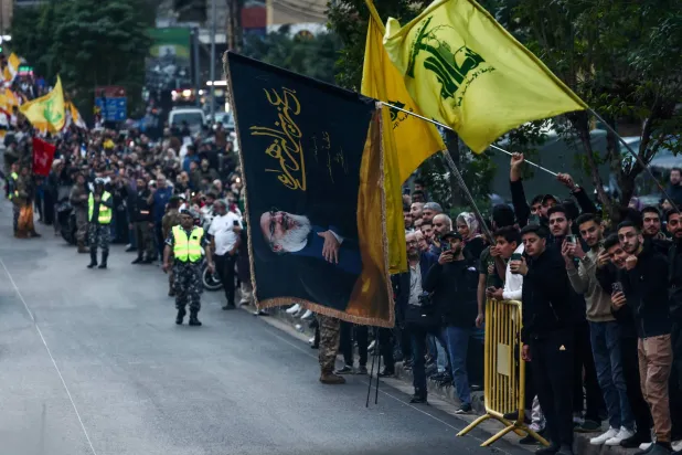 A person holds a flag with an image of late Hezbollah leader Hassan Nasrallah, as people wait for the arrival of Pope Leo XIV, during his first apostolic journey, in Beirut, Lebanon, November 30, 2025. REUTERS/Yara Nardi
