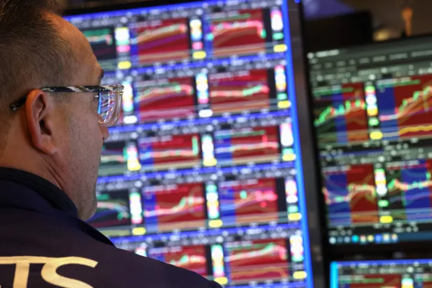 متداول يراقب شاشة تعرض مؤشرات الأسهم في بورصة نيويورك (رويترز)