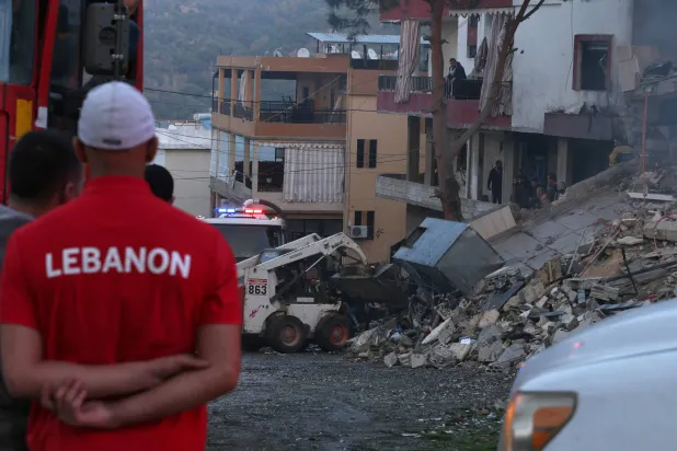 لبنانيون يشاهدون عمليات البحث عن ناجين في موقع غارة إسرائيلية استهدفت قرية جباع جنوب لبنان أمس (أ.ف.ب)
