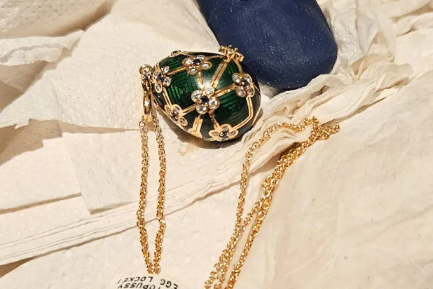 This handout photo release by New Zealand Police on December 5, 2025 shows an officer displaying a recovered diamond-encrusted green Fabergé egg in Auckland after keeping a six-day watch over the thief accused of swallowing it. (Photo by Handout / NEW ZEALAND POLICE / AFP)
