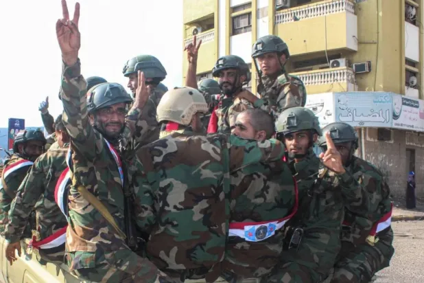 Yemeni armed forces flash the V-sign for victory as they ride in the back of a lorry as they celebrate the 58th anniversary of National Independence Day, in the port city of Aden, November 30, 2025. (Photo by Saleh Al-OBEIDI / AFP)