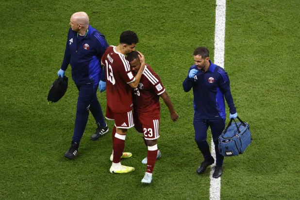 لاعب المنتخب القطري عاصم ماديبو لدى خروجه من الملعب مصاباً في مواجهة فلسطين (رويترز)