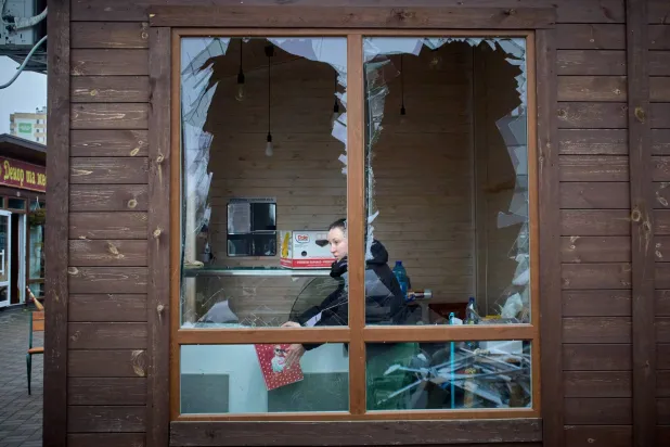 An owner of a small private shop is seen through the broken window waiting for customers after Russia's night missile attack on a residential neighborhood in Vyshgorod, outside Kyiv, Ukraine, Sunday, Nov. 30, 2025. (AP Photo/Efrem Lukatsky)