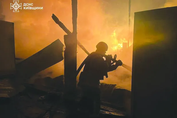 This handout photograph taken and released by the State Emergency Service of Ukraine on December 6, 2025, shows a firefighter extinguishing a fire at a site of an air attack in Kyiv region, amid the Russian invasion of Ukraine. (Photo by Handout / STATE EMERGENSY SERVICE OF UKRAINE / AFP)  