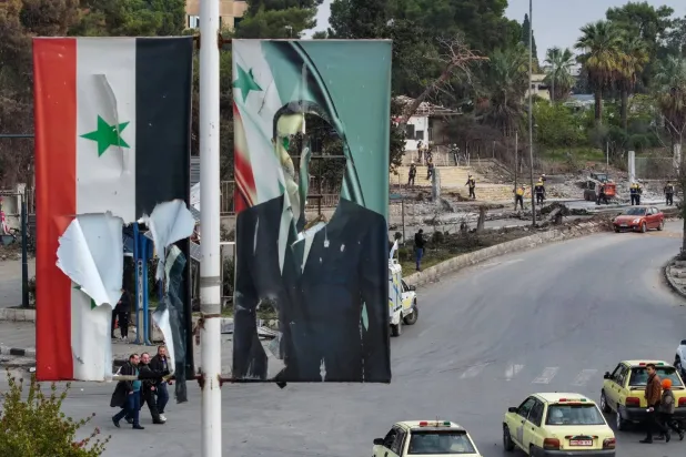 A tattered Syrian flag and Assad poster in Aleppo on Dec. 5, 2024. (AFP via Getty Images)