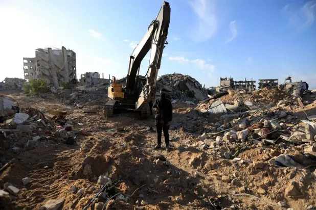 A Palestinian gunman stands guard as Hamas and Islamic Jihad fighters transport a white body bag believed to carry the remains of an Israeli hostage in the town of Beit Lahia in the northern Gaza Strip on December 3, 2025. (AFP)