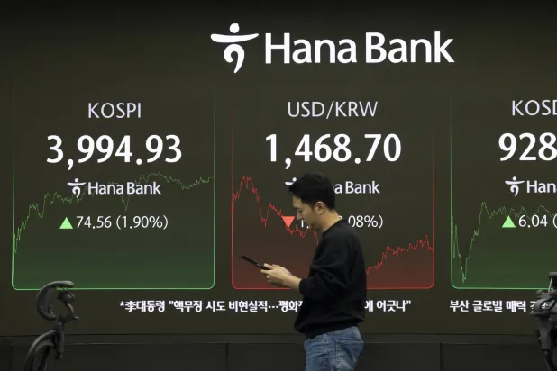 متداول يمر أمام شاشات تعرض مؤشر «كوسبي» ببنك هانا في سيول (إ.ب.أ)