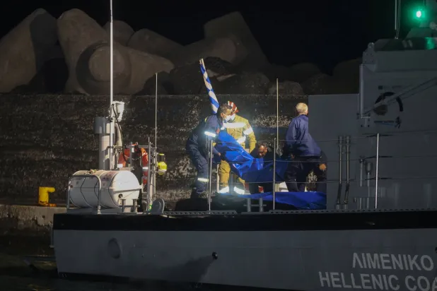 عناصر خفر السواحل في اليونان يحملون أكياساً تضم جثث مهاجرين غرقى (رويترز)