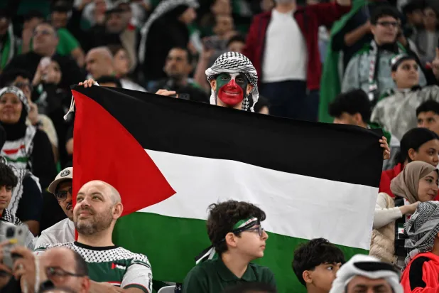 جماهير فلسطين تحتفل بالتأهل في ملعب المدينة التعليمية بالدوحة (أ.ف.ب) 