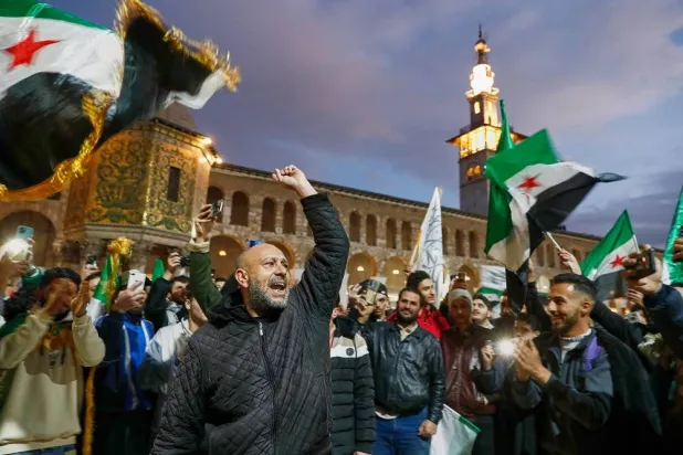 Syrians shout slogans and wave flags outside the Umayyad Mosque before a prayer held ahead of celebrations marking the first anniversary of the ousting of the Bashar al-Assad regime in Damascus, Syria, Monday, Dec. 8, 2025. (AP) 