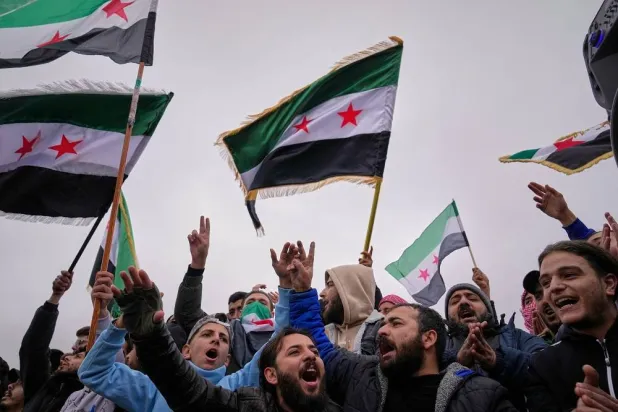 People celebrate and wave Syrian flags as they wait for a parade by the new Syrian army marking the first anniversary of the ousting of the Bashar al-Assad regime in Damascus, Syria, Monday, Dec. 8, 2025. (AP)