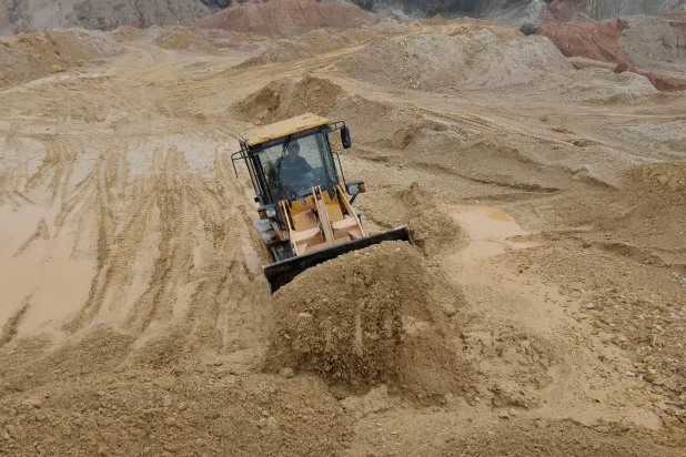 عامل يقوم برفع الرمال في موقع للمعادن النادرة في إقليم جيانغتشي الصيني (رويترز)