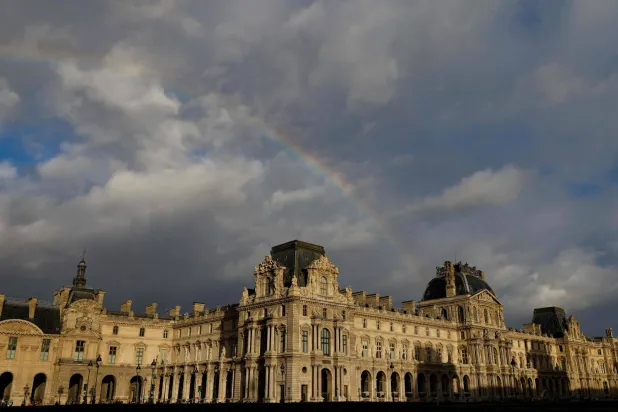 A rainbow emerges over the Louvre museum, bathed in late afternoon sunlight, in Paris, on December 6, 2025. (AFP)