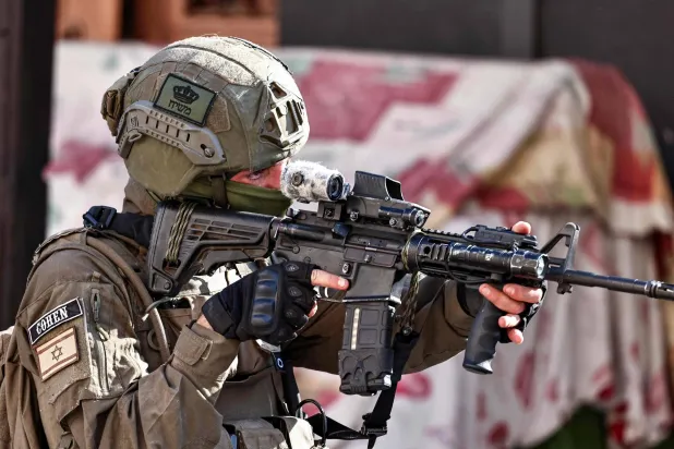 جندي إسرائيلي يوجِّه سلاحه خلال عملية عسكرية في بلدة قلقيلية بالضفة الغربية (أ.ف.ب)