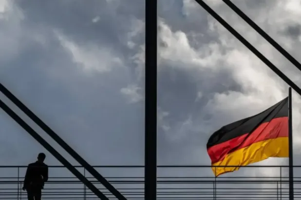 A man pauses on a pedestrian bridge as a German flag flies over the Reichstag building in Berlin on October 23, 2024. (AFP)
