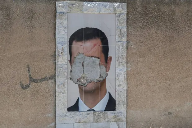 A defaced portrait of Syria's ousted President Bashar al-Assad hangs on a wall in the capital Damascus on June 2, 2025. (AFP)