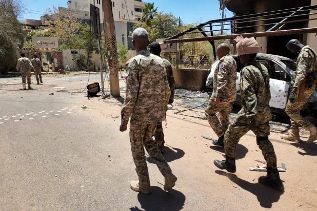 أفراد من الجيش السوداني يسيرون بجوار مركبات عسكرية مدمرة في العاصمة السودانية الخرطوم (رويترز - أرشيفية)