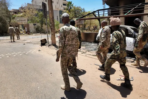 Sudan askerleri, başkent Hartum'da tahrip edilmiş askeri araçların yanından geçiyor (Arşiv-Reuters)