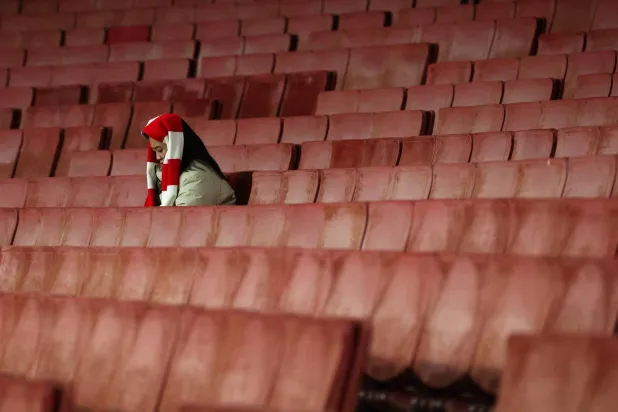 A lone Arsenal fan sits in the stands ahead of the English Premier League football match between Arsenal and Brentford at the Emirates Stadium in London on December 3, 2025. (AFP)