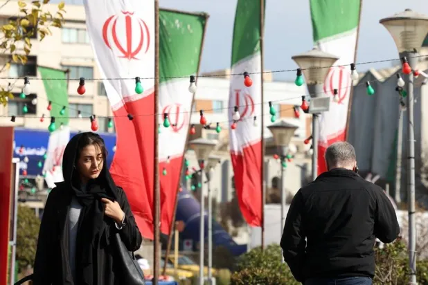 Iranians walk past Iran's national flag on a street in Tehran, Iran, 10 December 2025. (EPA)
