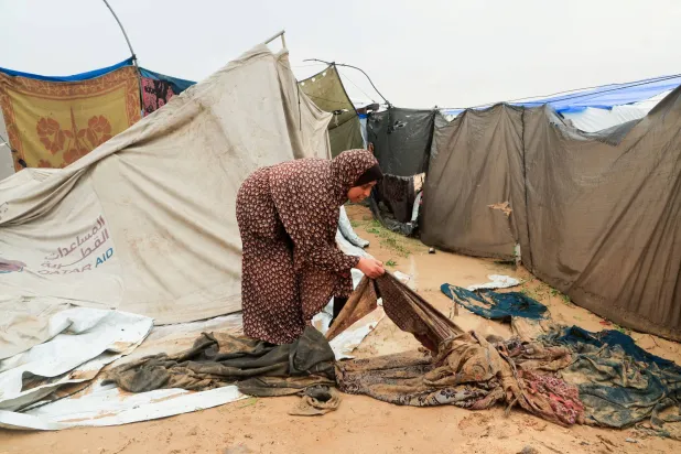 فلسطينية نازحة بأحد المخيمات في يوم ممطر بخان يونس جنوب قطاع غزة (رويترز)