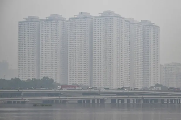 This picture shows vehicles driving on a highway amid heavy air pollution conditions in Hanoi on December 11, 2025. (Photo by NHAC NGUYEN / AFP)