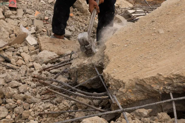 A Palestinian worker breaks concrete to extract steel bars from destroyed homes, using only simple hand tools amid a severe shortage of construction materials caused by long-standing restrictions on the entry of cement and iron, in Khan Younis, southern Gaza Strip, December 9, 2025. REUTERS/Haseeb Alwazeer
