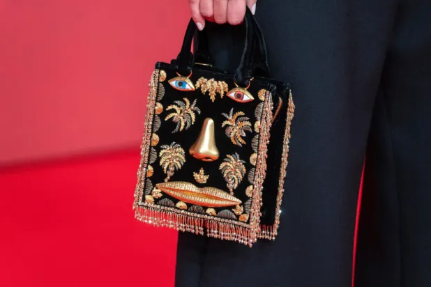 An actress holds a Schiaparelli purse while posing for a photo on the red carpet during 22nd Marrakech Film Festival, in Morocco, Tuesday, Dec. 2, 2025. (AP Photo/Mosa’ab Elshamy)

