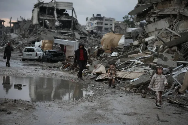 Palestinians walk through the rubble amid stormy weather in Gaza City Thursday, Dec. 11, 2025. (AP Photo/Jehad Alshrafi)