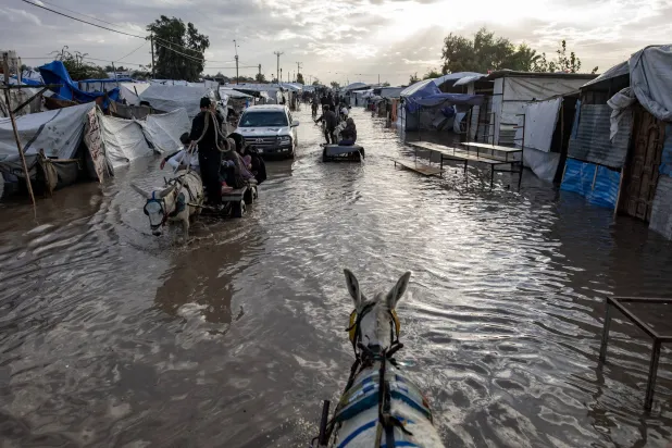 Displaced Palestinians make their way on animal-drawn carts through a flooded street following heavy rainfall in Khan Younis in southern Gaza, 11 December 2025. EPA/HAITHAM IMAD