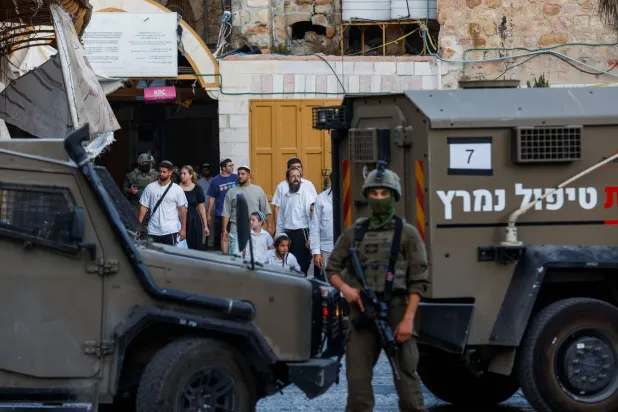 جندي إسرائيلي يقف لحماية المشاركين في جولة أسبوعية للمستوطنين في الخليل بالضفة الغربية المحتلة (أرشيفية - رويترز)