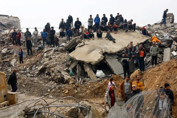 فلسطينيون خلال البحث عن ضحايا تحت أنقاض منزل انهار تحت المطر الغزير في بيت لاهيا شمال قطاع غزة الجمعة (رويترز)