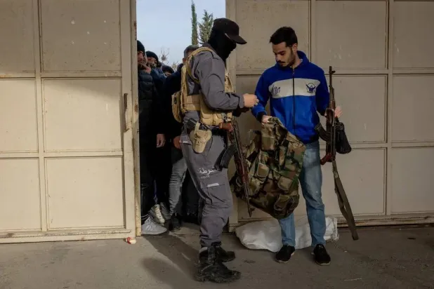 Soldiers and police officers from the former Syrian regime handing in weapons last year to new security forces in Latakia, Syria. (Ivor Prickett for The New York Times)