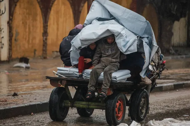 Two boys shelter from the rain while sitting on a donkey cart in Deir al Balah in the central Gaza Strip (AFP)