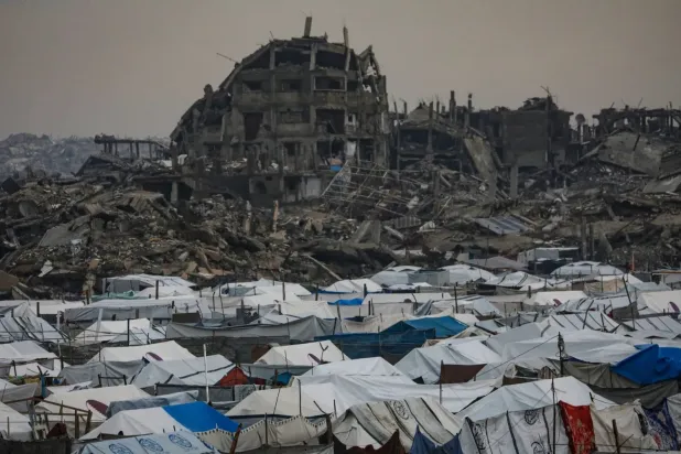 Gazze şehrinin doğusundaki Zeytun mahallesinde, arkalarında yıkılmış binaların görüldüğü Filistinli mülteci çadırları (EPA)