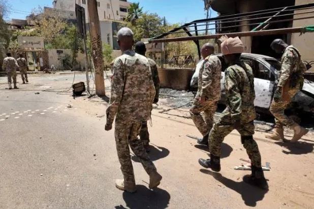 جنود من الجيش السوداني يسيرون بجوار مركبات عسكرية مدمرة بعد معركة مع «قوات الدعم السريع» في الخرطوم (رويترز)