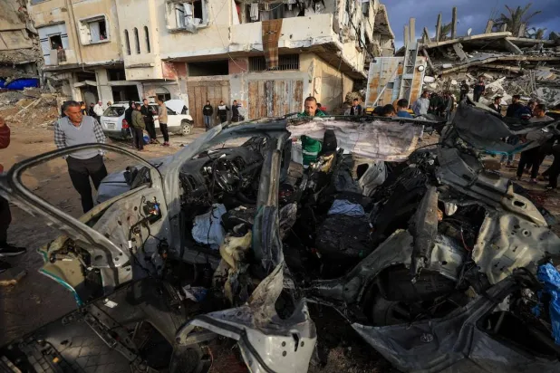 Palestinians inspect the site of an Israeli strike on a car in Gaza City, December 13, 2025. (Reuters)