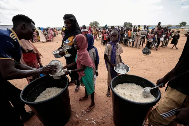 FILE PHOTO: Sudanese people, who fled the conflict in Geneina in Sudan's Darfur region, receive rice portions from Red Cross volunteers in Ourang on the outskirts of Adre, Chad July 25, 2023. REUTERS/Zohra Bensemra/File Photo