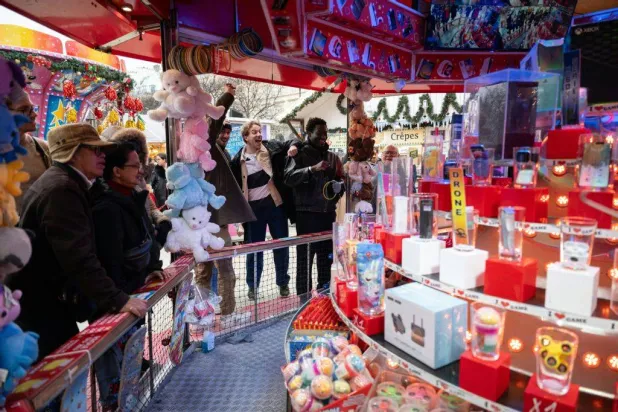 Visitors participate in a game at the Christmas market and fairground in the Jardin des Tuileries gardens in central Paris, on December 13, 2025. (Photo by Anna KURTH / AFP)